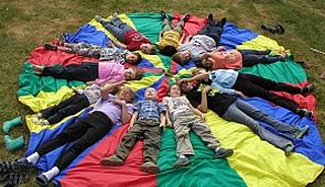 Kinder auf einem Schwungtuch - Kinder liegen im Kreis auf einen Schwungtuch